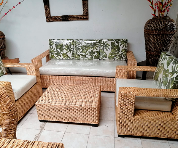 Juego de sala de mimbre artesanal con sofá, dos poltronas y mesa de centro.